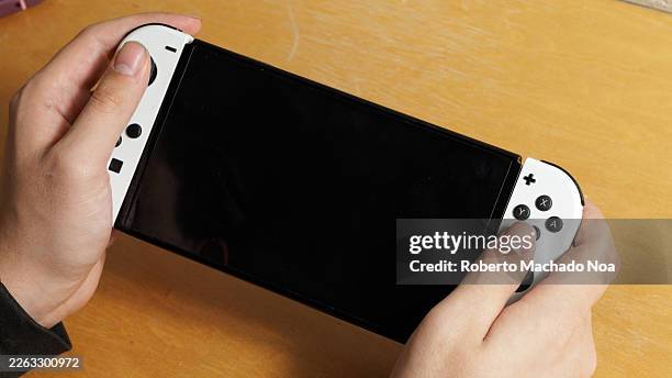 In this photo illustration, hands holding a Nintendo Switch in handheld mode.