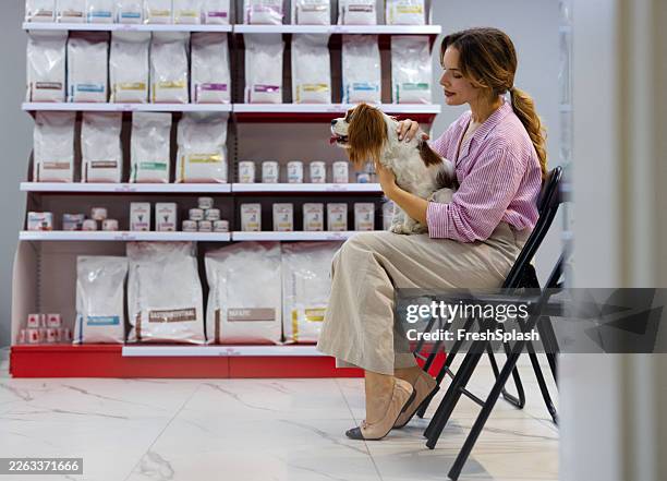 woman holding small dog in pet store aisle - pet shop stock pictures, royalty-free photos & images