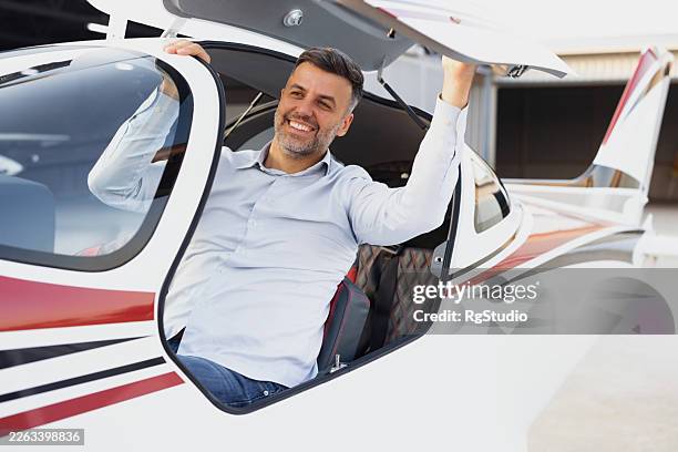 man pilot exiting private plane from hangar - private airplane stock pictures, royalty-free photos & images