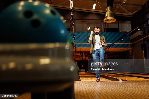 glücklicher junger bowler jubelt nach dem sieg in der bowlingbahn - bowlingbahn stock-fotos und bilder