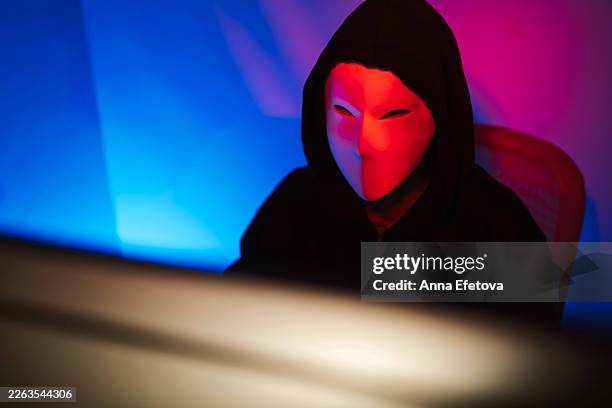 hacker wearing anonymity mask using computer in darkness - regulatory update stock pictures, royalty-free photos & images