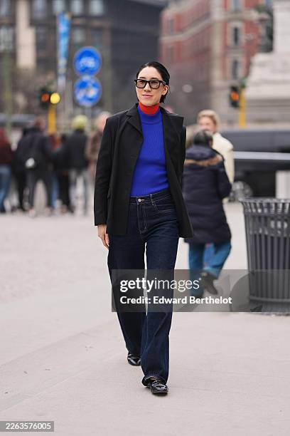 Eva Chen wears black sunglasses, a black tailored blazer, a blue knit turtleneck sweater layered with a red knit turtleneck, dark blue denim wide leg...