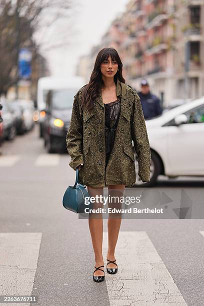 Guest wears dark brown hair with bangs, a green khaki with black rhinestones embellished oversized jacket, a black lace sheer fitted camisole short...