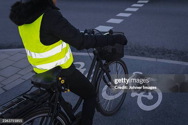 woman in reflective clothes waiting with cycle at roadside - reflector stock pictures, royalty-free photos & images