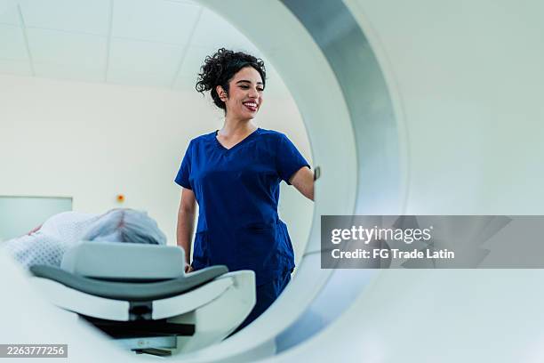mid adult nurse during magnetic resonance exam at hospital - radiologist stock pictures, royalty-free photos & images