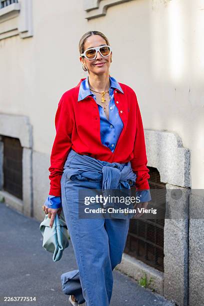 Tiany Kiriloff wears blue blouse, red cardigan, blue pants, bag, white sunglasses outside Anteprima during the Milan Fashion Week - Womenswear...
