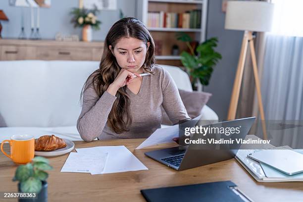 joven centrada en finanzas trabajando desde casa - deuda estudiantil fotografías e imágenes de stock