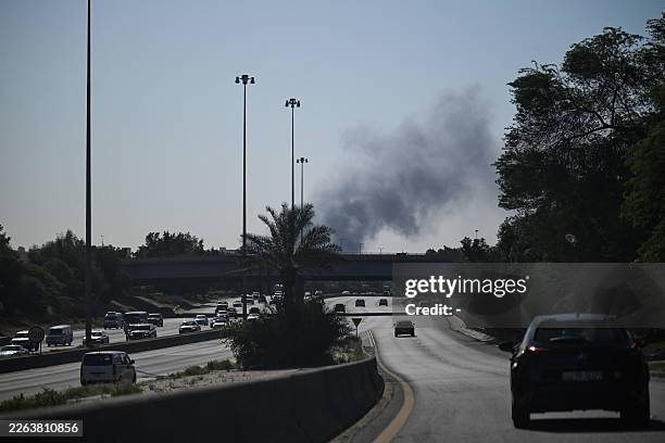 Motorists drive along a street as smoke rises from a reported Iranian strike in the area where the US Embassy is located in Kuwait City on March 2,...