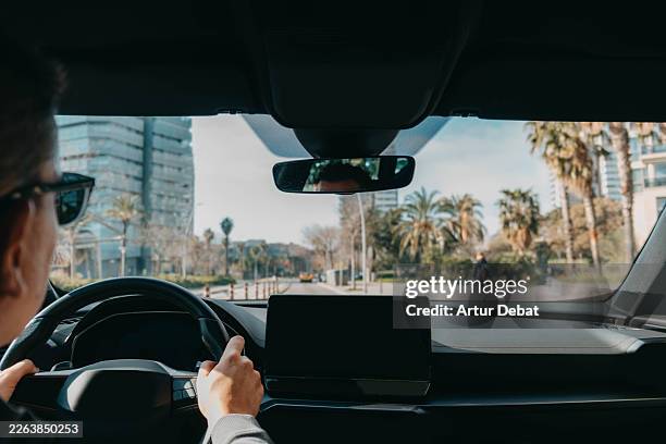 rideshare driver behind the steering wheel driving in urban city with palm trees - cuadro de instrumentos fotografías e imágenes de stock