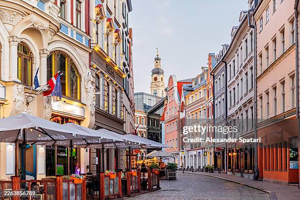 colourful illuminated street with cafes and restaurants in riga medieval old town at dusk in summer, latvia - riga stock pictures, royalty-free photos & images