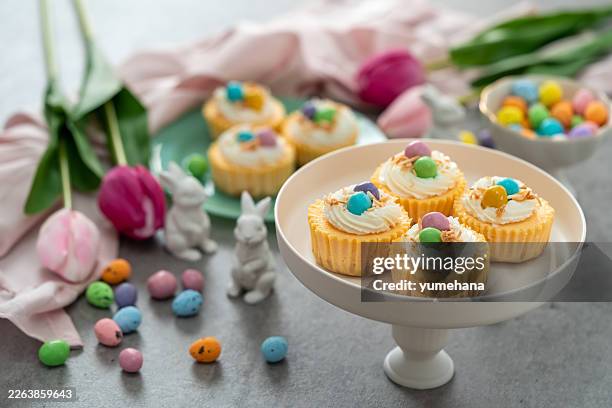 mini cheesecake bird's nest with whipped cream and mini candy eggs for easter dessert. - easter cupcake stock pictures, royalty-free photos & images