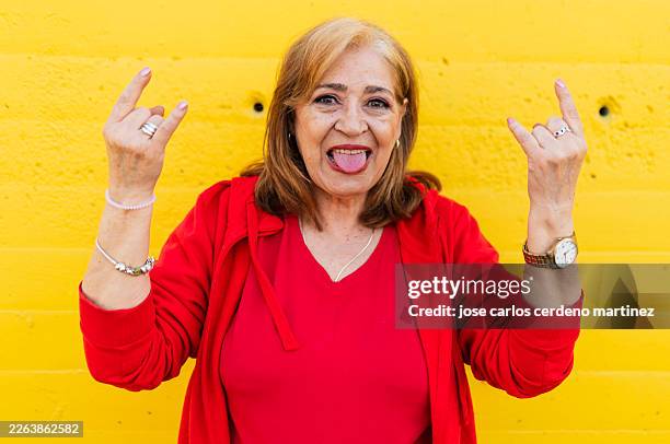 senior woman making rock and roll hand gesture - horn sign stock pictures, royalty-free photos & images