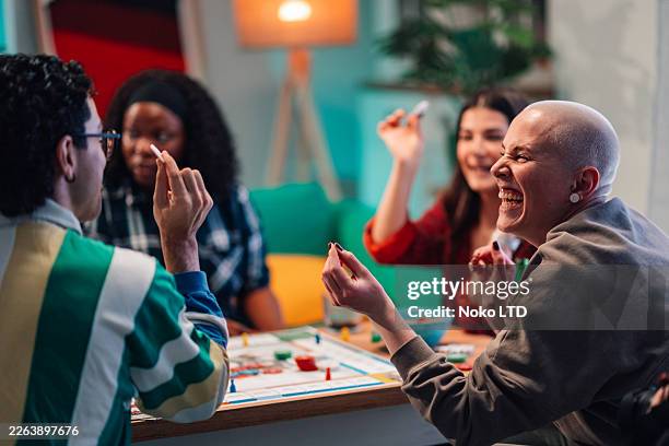 diverse friends laughing and playing a board game together during a cozy game night at home - bordspel stockfoto's en -beelden