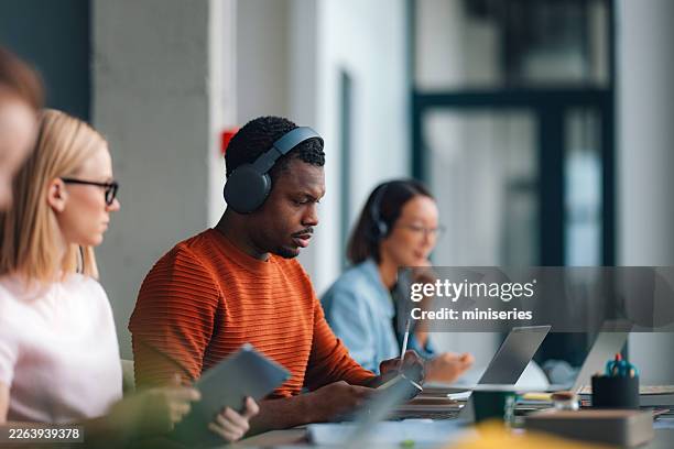 focused students studying together in a modern university library with laptops and headphones - virtual library stock pictures, royalty-free photos & images