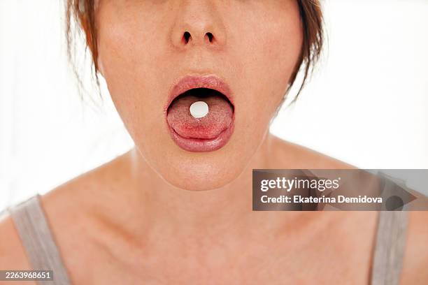 woman holding white pill on tongue taking medicine - tongue stock pictures, royalty-free photos & images