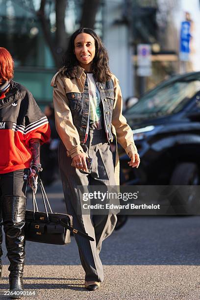 Guest wears a beige cotton denim colorblock jacket, a white cotton graphic T-shirt, gray wool pinstriped wide leg trousers, black leather ballet...