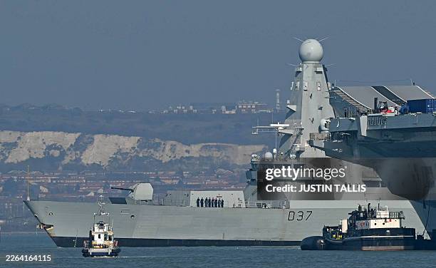Duncan, a Royal Navy Type 45 Daring-class air-defence destroyer warship, passes Royal Navy Aircraft Carrier HMS Prince of Wales as it departs from HM...