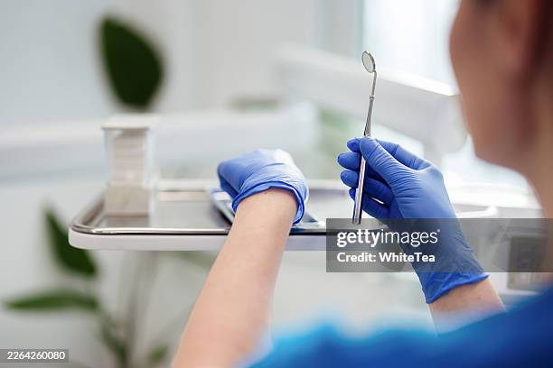 dentist holding dental mirror over tray in clinic - surgical glove stock pictures, royalty-free photos & images