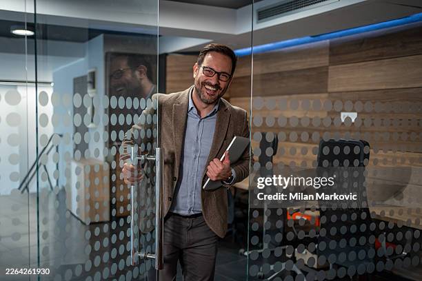 uomo d'affari felice che entra in ufficio moderno portando un portatile - entrare foto e immagini stock
