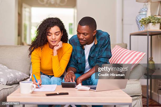 young couple budgeting at home with laptop and calculator on living room sofa - budget stock pictures, royalty-free photos & images