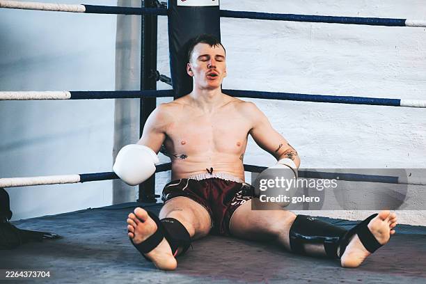 young martial arts fighter resting in boxing ring after fight - mixed martial arts stock pictures, royalty-free photos & images