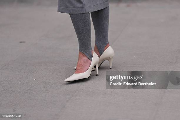 Guest wears a gray wool straight coat, gray knit stirrup leggings, white leather pumps shoes, outside Jil Sander, during Milan Fashion Week -...