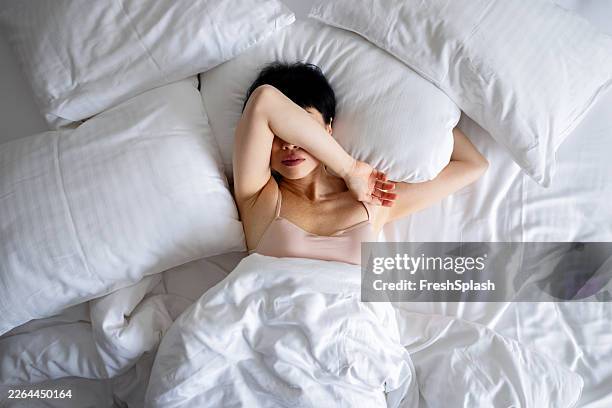 donna che riposa in un letto bianco con cuscino e coperta - supino foto e immagini stock