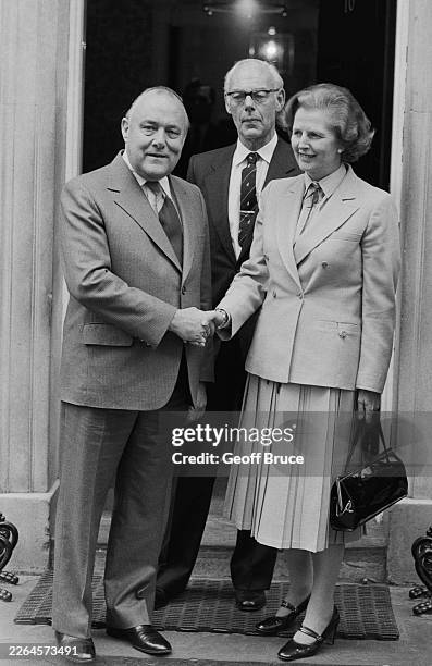 British Prime Minister Margaret Thatcher handshaking with New Zealand PM Robert Muldoon, left, as Dennis Thatcher stands behind outside 10 Downing...