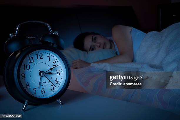 woman lying awake in bed, struggling with insomnia and restlessness. - insomnia stock pictures, royalty-free photos & images