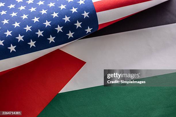 the interlacing of the flags of the united states of america and palestine, symbolizing the complex geopolitical tensions and long-standing diplomatic influence of the united states in the middle east region - tous les drapeaux du moyen orient photos et images de collection