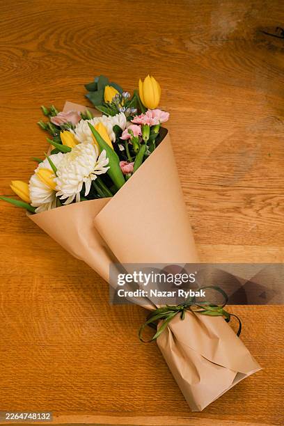 fresh flower bouquet wrapped in craft paper on wooden table - bouquet stock pictures, royalty-free photos & images