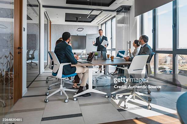 business meeting in modern office with colleagues presenting strategy at conference table - executive director stock pictures, royalty-free photos & images