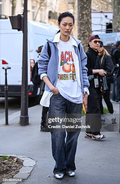 Model Ruiyi Zhang is seen wearing a blue jacket, white and orange shirt, blue jeans, silver shoes outside the Dries Van Noten show during Day Three...