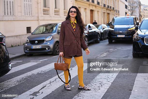 Guest wears dark brown hair, black sunglasses, a dark brown suede gold studded blazer jacket, a matching dark brown suede gold studded mini skirt, a...