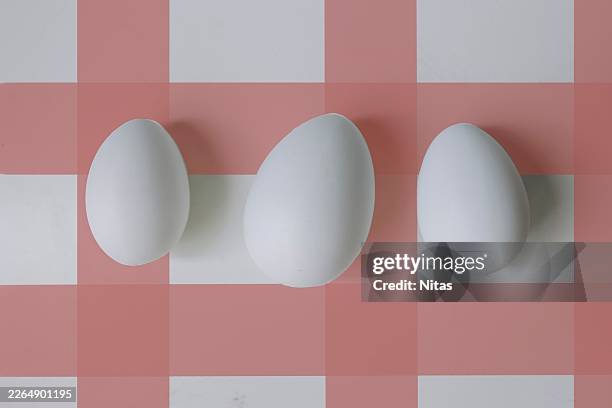 three white eggs on pink gingham background for easter - easter breakfast stock pictures, royalty-free photos & images