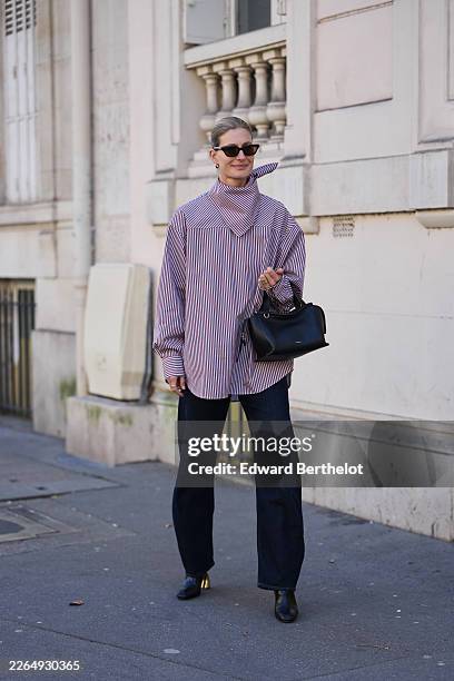 Guest wears blonde hair in a bun, black cat eyes sunglasses, a purple and white cotton striped print pattern oversized button-up shirt with a...