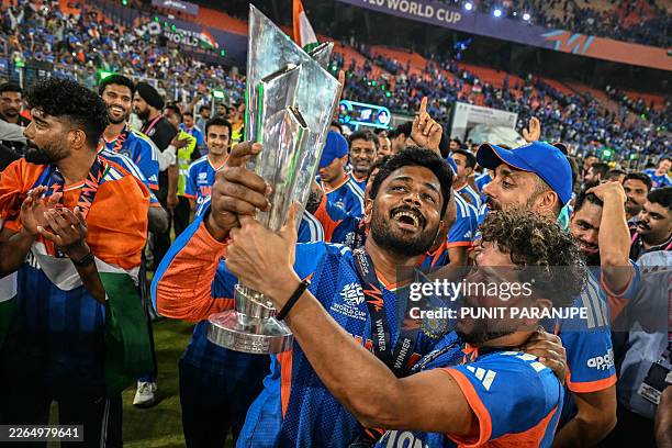 India's Sanju Samson and Kuldeep Yadav celebrate with the trophy during a victory lap after winning the 2026 ICC Men's T20 Cricket World Cup final...