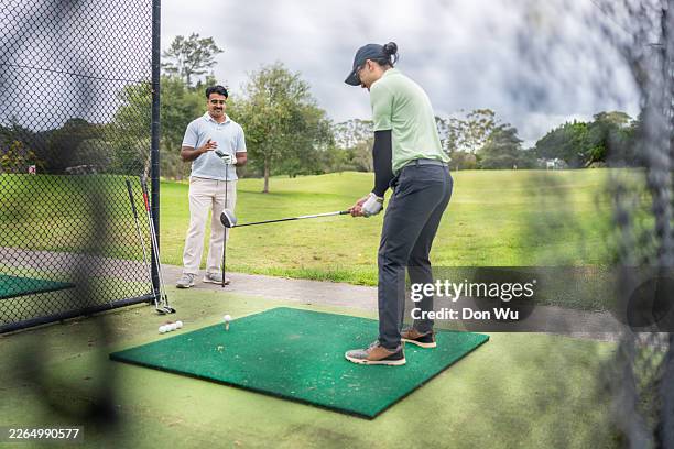 two men practicing golf at driving range - driving range stock pictures, royalty-free photos & images