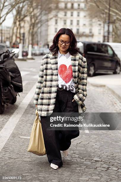 Amy Nathalie Portier wears a black, cream and green plaid wool jacket layered over a white button-down shirt and a white T-shirt with a large red...