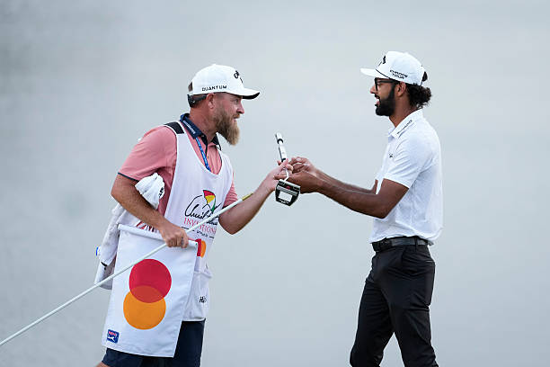 Akshay Bhatia celebrates hands his putter over to his caddie, Joe Greiner, after winning on the first playoff hole during the final round of Arnold...