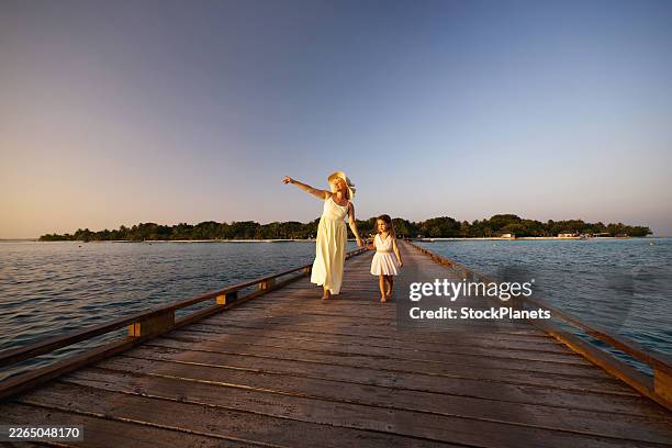 une mère heureuse montrant quelque chose à sa fille lors d’une promenade d’été sur la jetée en mer. - ponton photos et images de collection