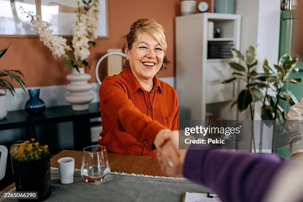 female advisor shaking hands with senior woman at the home - credit union stock pictures, royalty-free photos & images