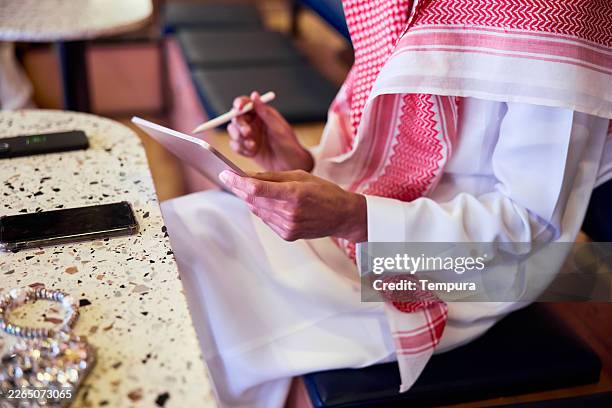 a workshop participant notes on a digital tablet. a man is seated in an auditorium, writing on his digital device. - saudi classroom stock pictures, royalty-free photos & images