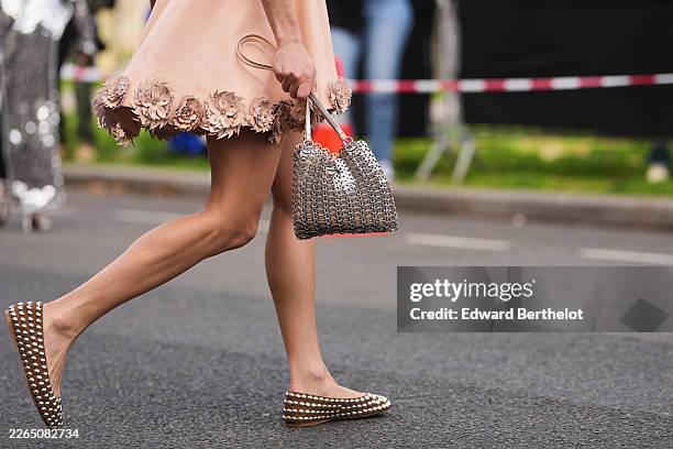 Yousra Mohsen wears an orange pink silk with embroidered leather flower pattern and silver nails / studs details / sleeveless mini dress, a silver...