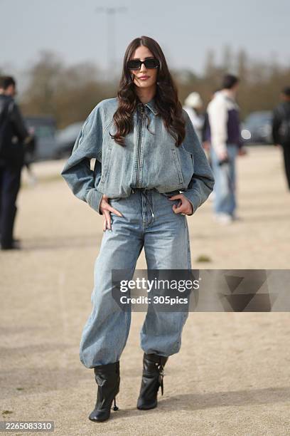 Person is seen wearing black rectangular sunglasses, a light wash denim bomber jacket with a front zipper and elasticized hem, light wash denim baggy...