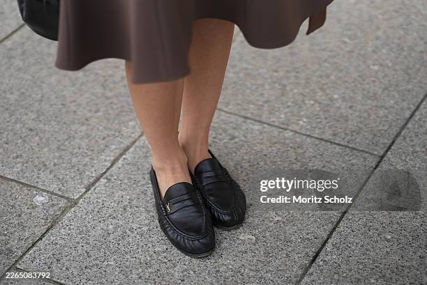 Dominique Nurtsch is seen wearing a dark brown flared "Sculptured Midi Skirt" with a smooth structured finish and A line silhouette from Arakii;...