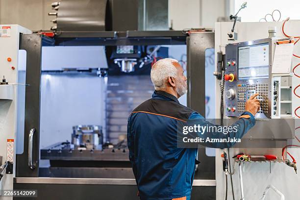 engaged technician managing cnc machine controls in high-tech workshop environment - cnc machine stock pictures, royalty-free photos & images