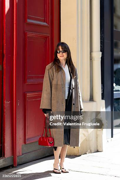 Guest wears black leather heeled flip-flops, a beige suede jacket, a white sweater, a black blazer and a red leather bag outside The Row show during...