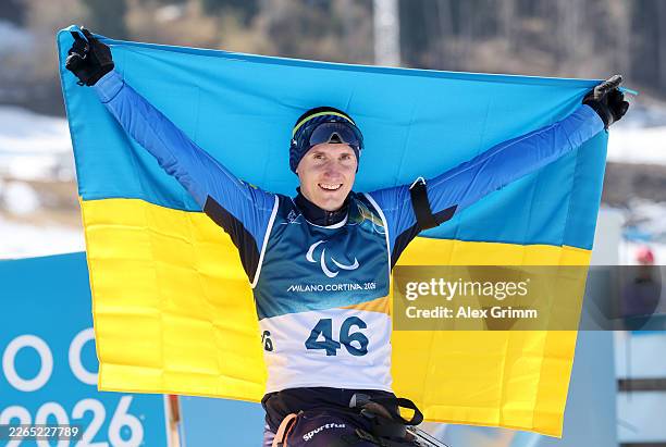 Taras Rad of Team Ukraine celebrates with the flag following his victory during the Para Biathlon Men's Sprint Sitting on day one of the Milano...