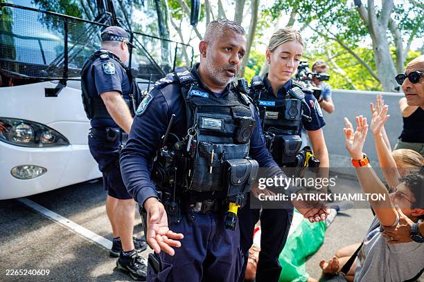 Police officers react as members of the Iranian community in Australia block the path of a departing bus transporting members of the Iranian Women's...